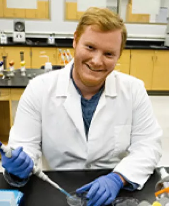 澳门线上博彩 Transfer Student Jarrett Stites holds a pipet in biology lab.