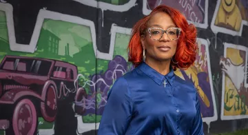 澳门线上博彩 Professor, Corinice Wilson, Ph.D. stands in front of the mural at Black Wall St..