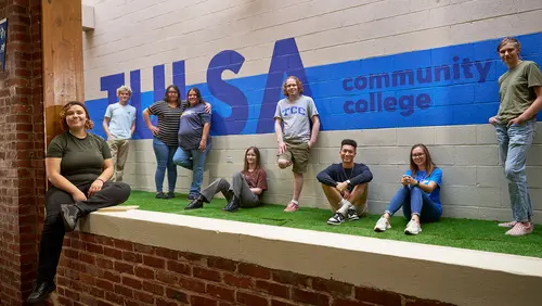 Students from Tulsa Community College stand together in front of a mural in the Fireplace lounge at 澳门线上博彩 Metro Campus.