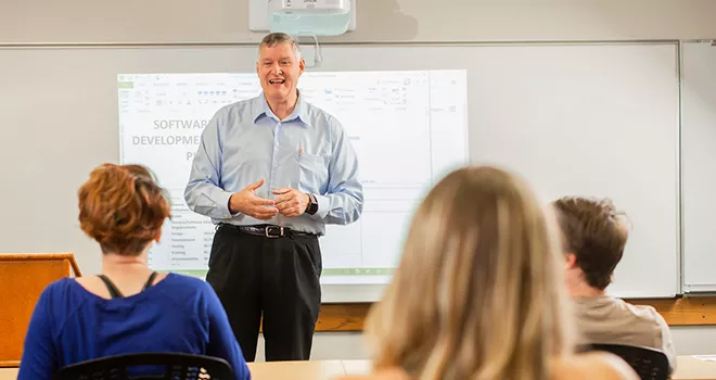 澳门线上博彩 business professor stands in front of a class of students.