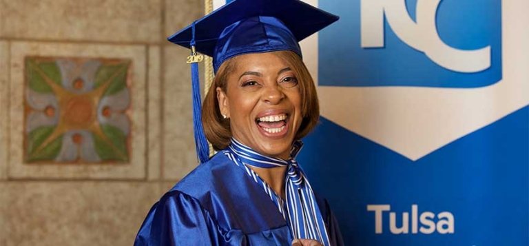 Smiling black woman wears her 澳门线上博彩 graduation cap and gown.