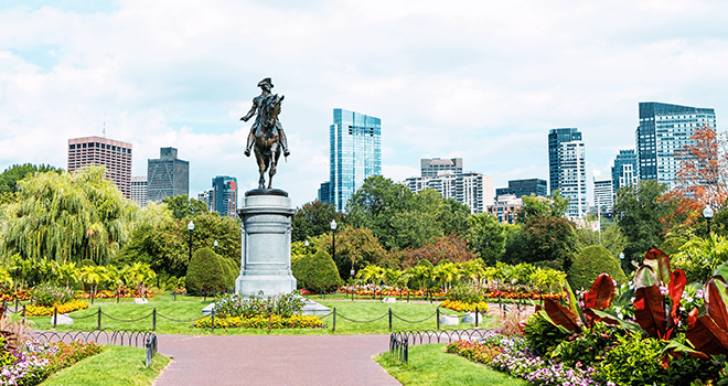 Modern buildings and flowers in park featuring a statue of Paul Revere in Boston city